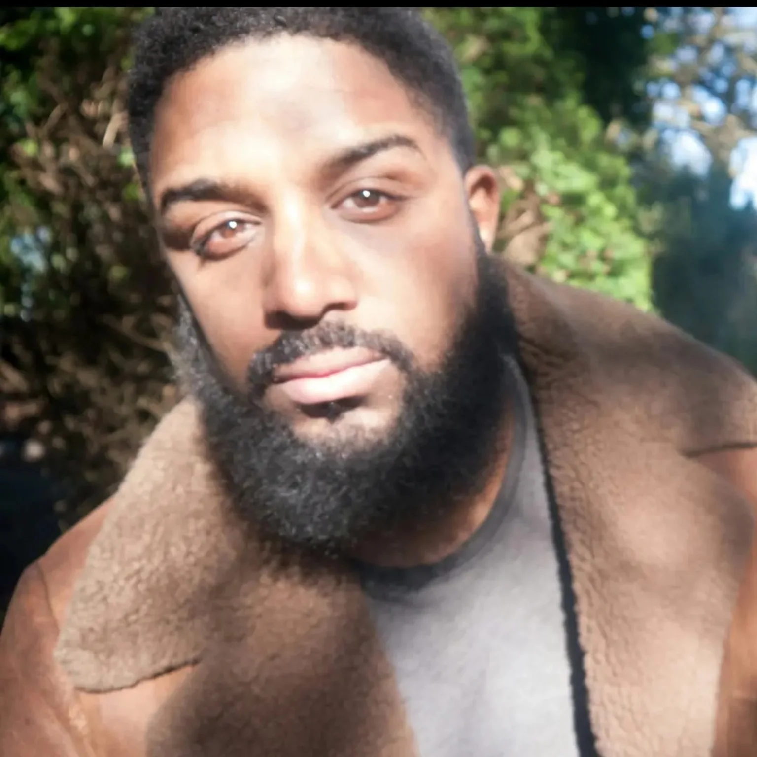 Évian Cafun outdoors wearing a brown shearling coat