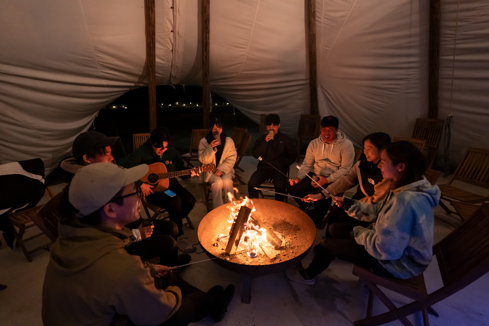 Guests around a fire inside the tent at night