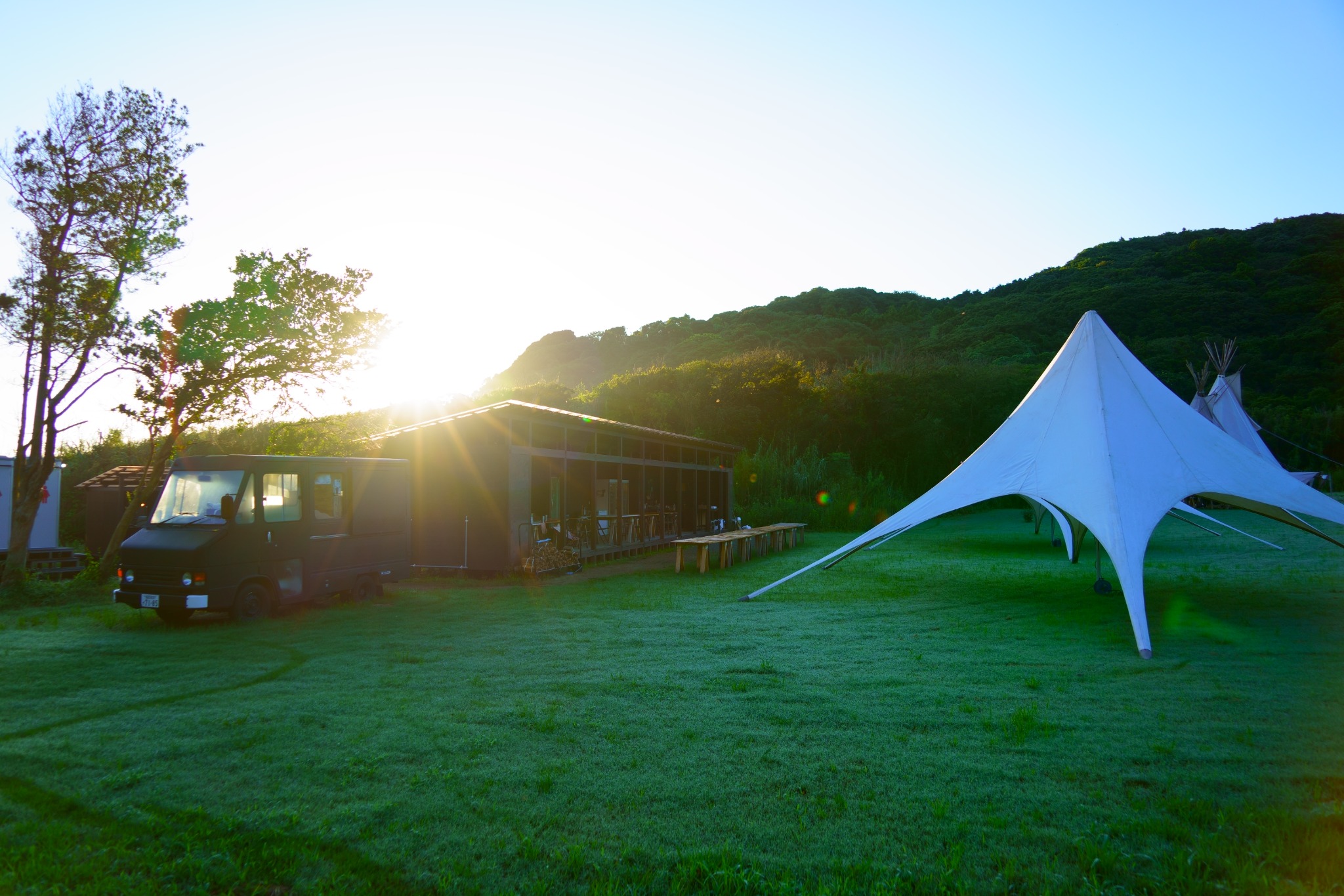 Sharkbeams venue at sunset with large outdoor tent and green hillside