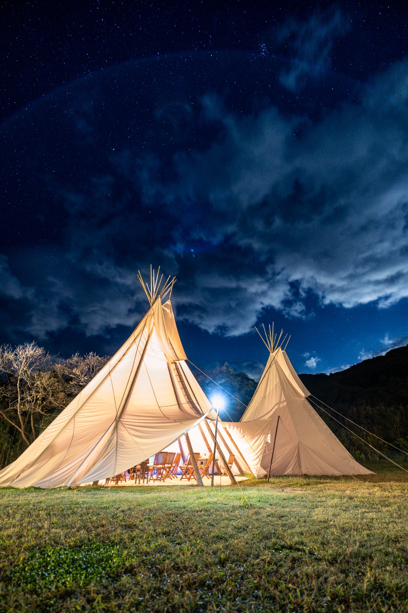 Lit glamping tents under a starry night sky