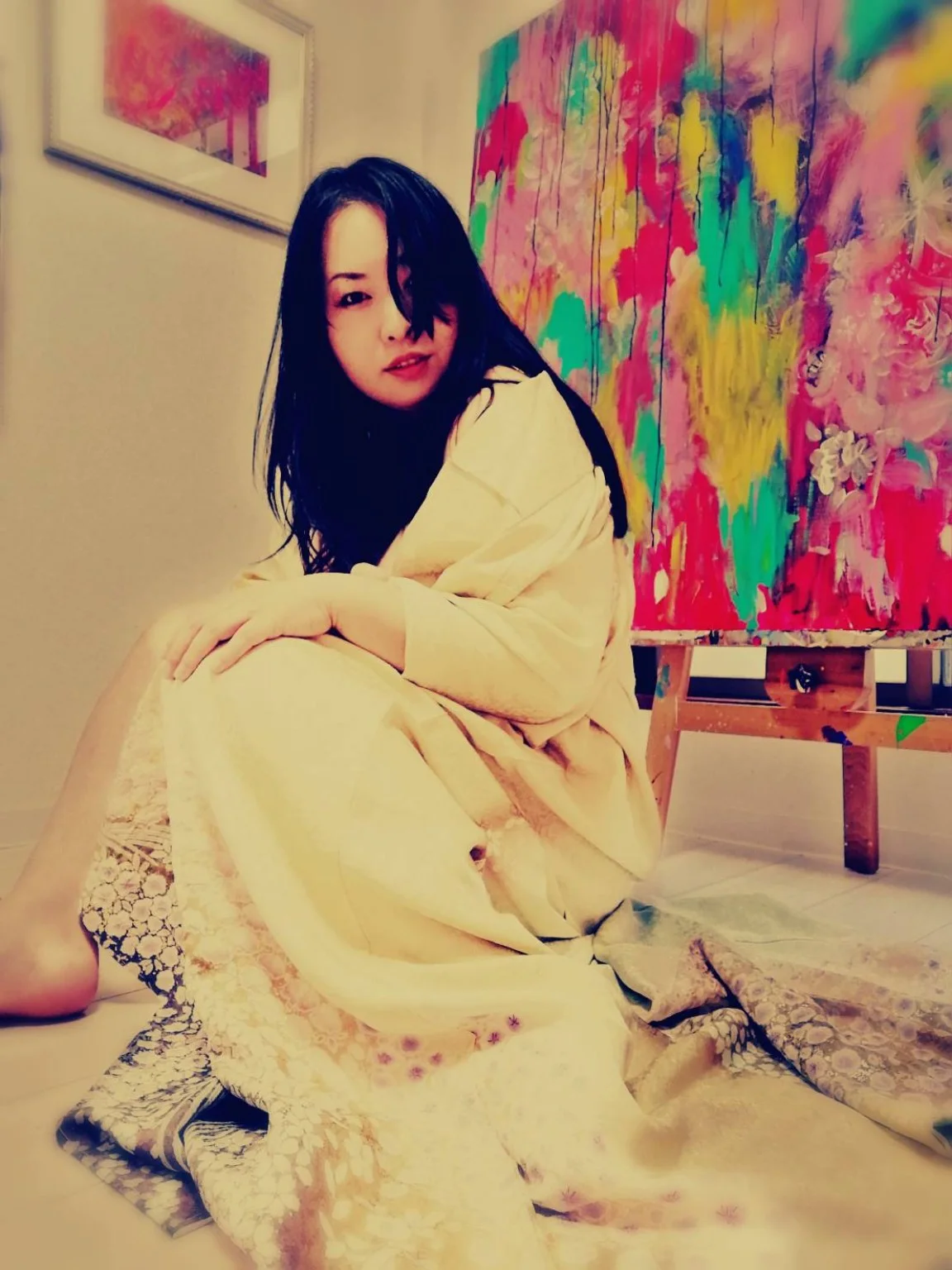 Yuuki seated in her studio beside a large painting